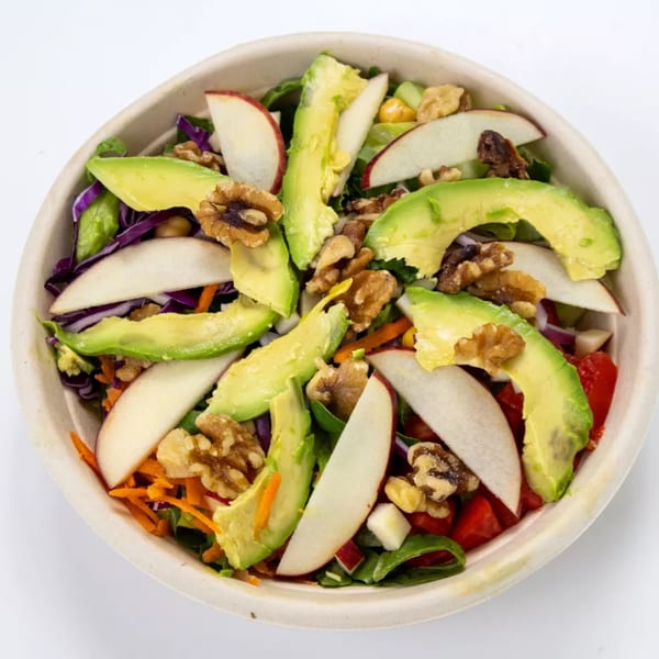 Colorful salad with avocado slices, apple wedges, walnuts, and mixed greens in a bowl.